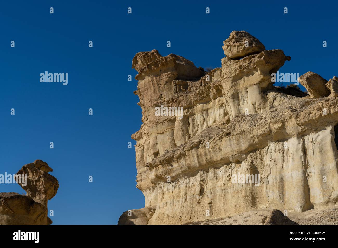 Una vista delle famose erosioni di arenaria e degli hoodoos a Bolnuevo sotto un cielo blu chiaro Foto Stock