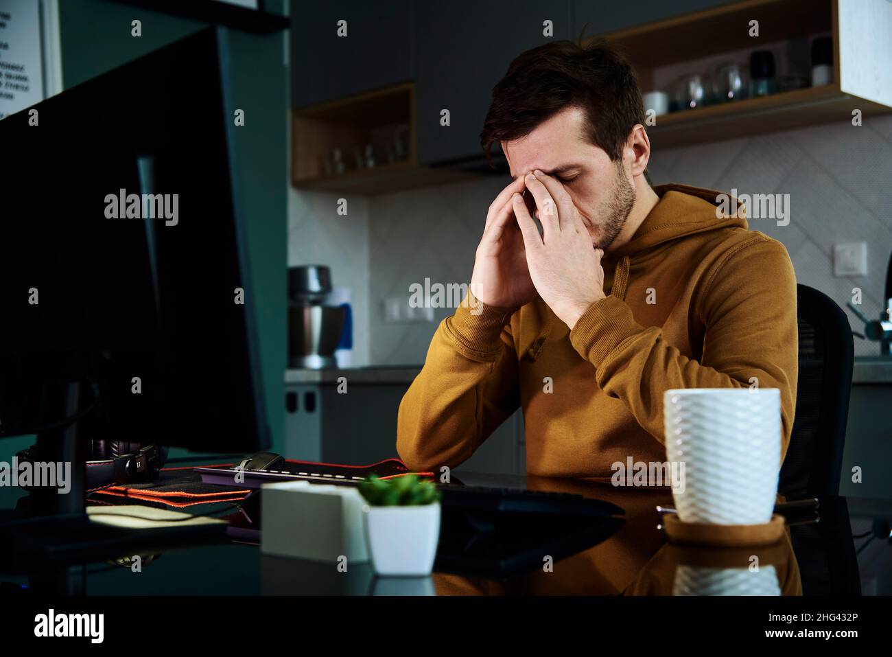 L'uomo lavora a casa in ritardo, concetto di lavoro remoto. Burnout e stress emotivo a causa di un lavoro eccessivo Foto Stock