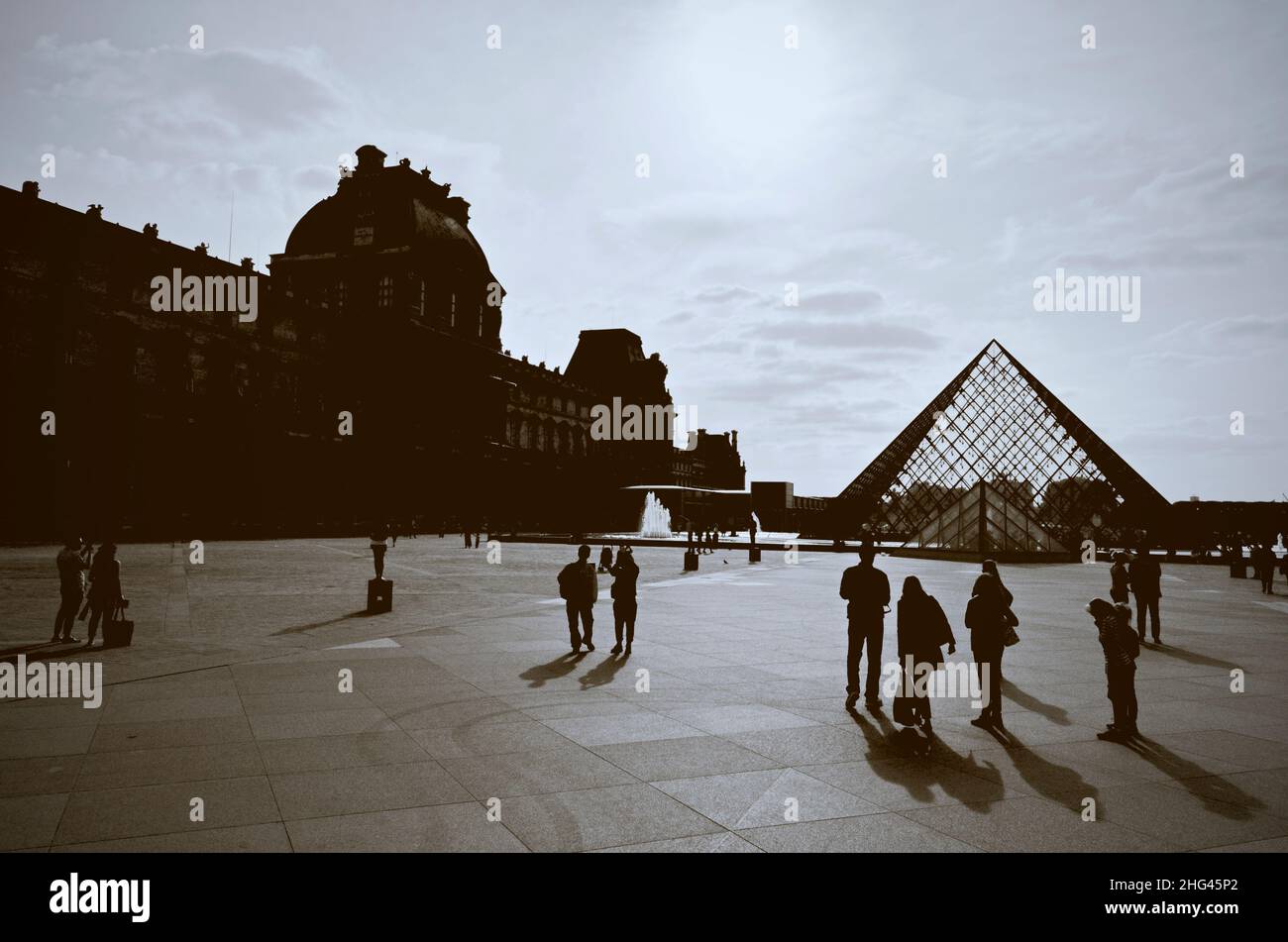 Fotografia contro la luce nella piazza del Museo del Louvre a Parigi, silhouette di turisti e visitatori Foto Stock