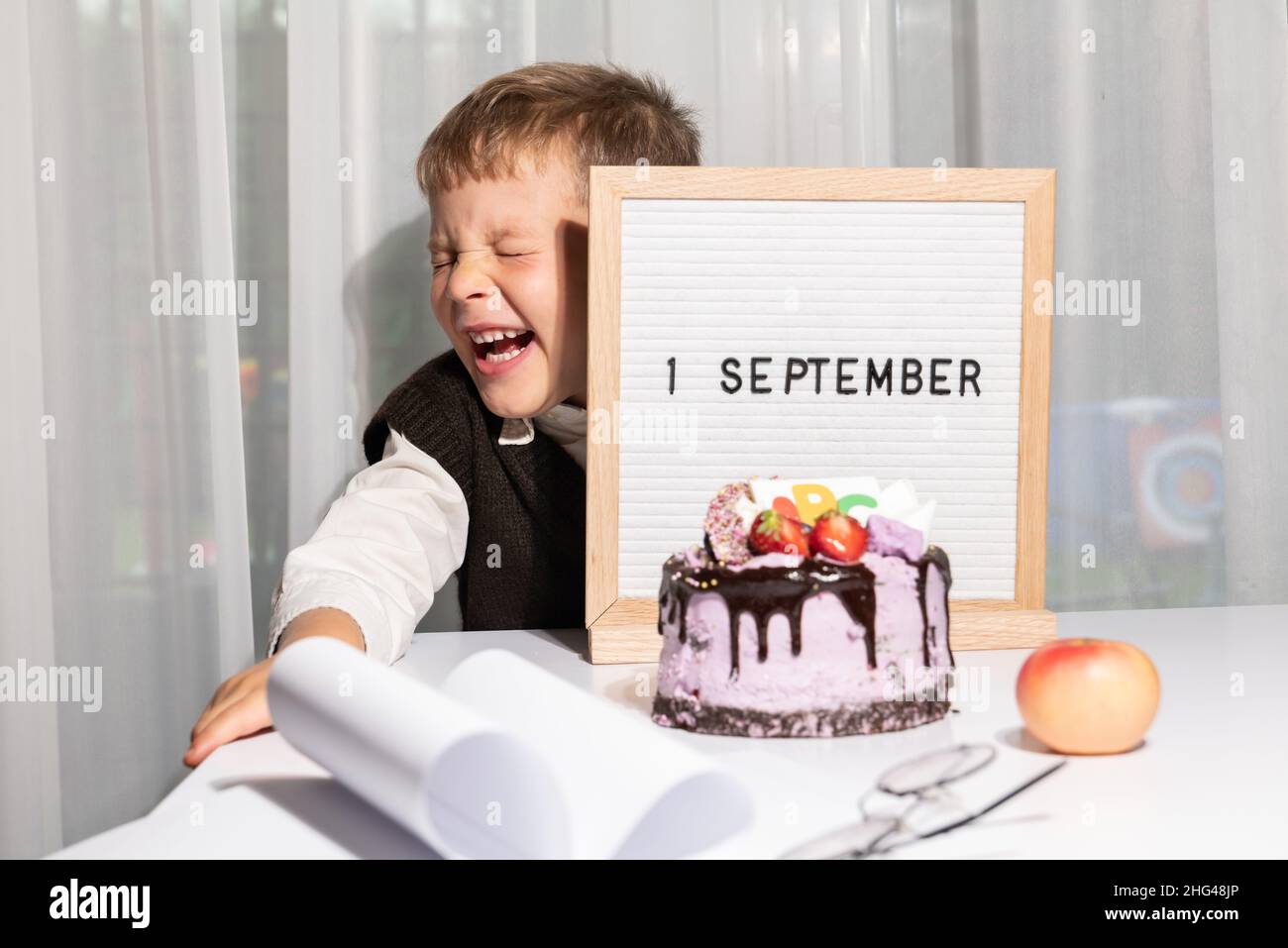 Adorabile ragazzo allegro in bicchieri mostra lettera bordo con testo 1 settembre, festa torta con ABC. Giornata della conoscenza. Concetto di istruzione, torna a sc Foto Stock