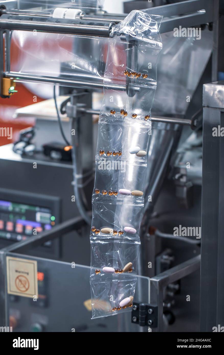 Pillole mediche riempite in macchina di riempimento della busta. Bustina di plastica riempita con vitamine o pillole in macchina automatica per il confezionamento degli alimenti. Foto Stock