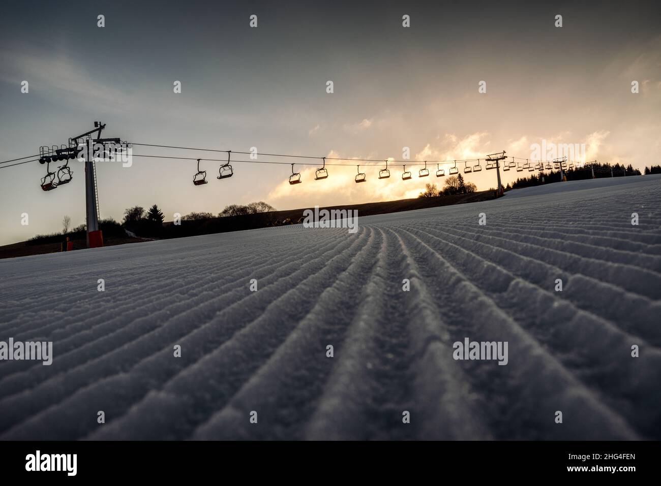 Nuova pista da sci curata o pista fresca. Skilift vuoto sullo sfondo. Foto Stock