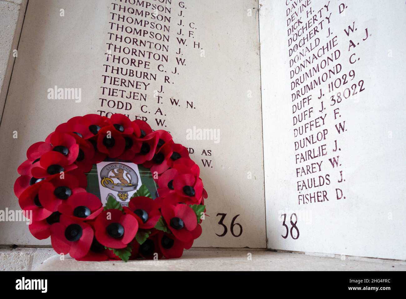 Una corona di papaveri si trova di fronte alle iscrizioni alla porta Menin di Ypres, in Belgio. Foto Stock