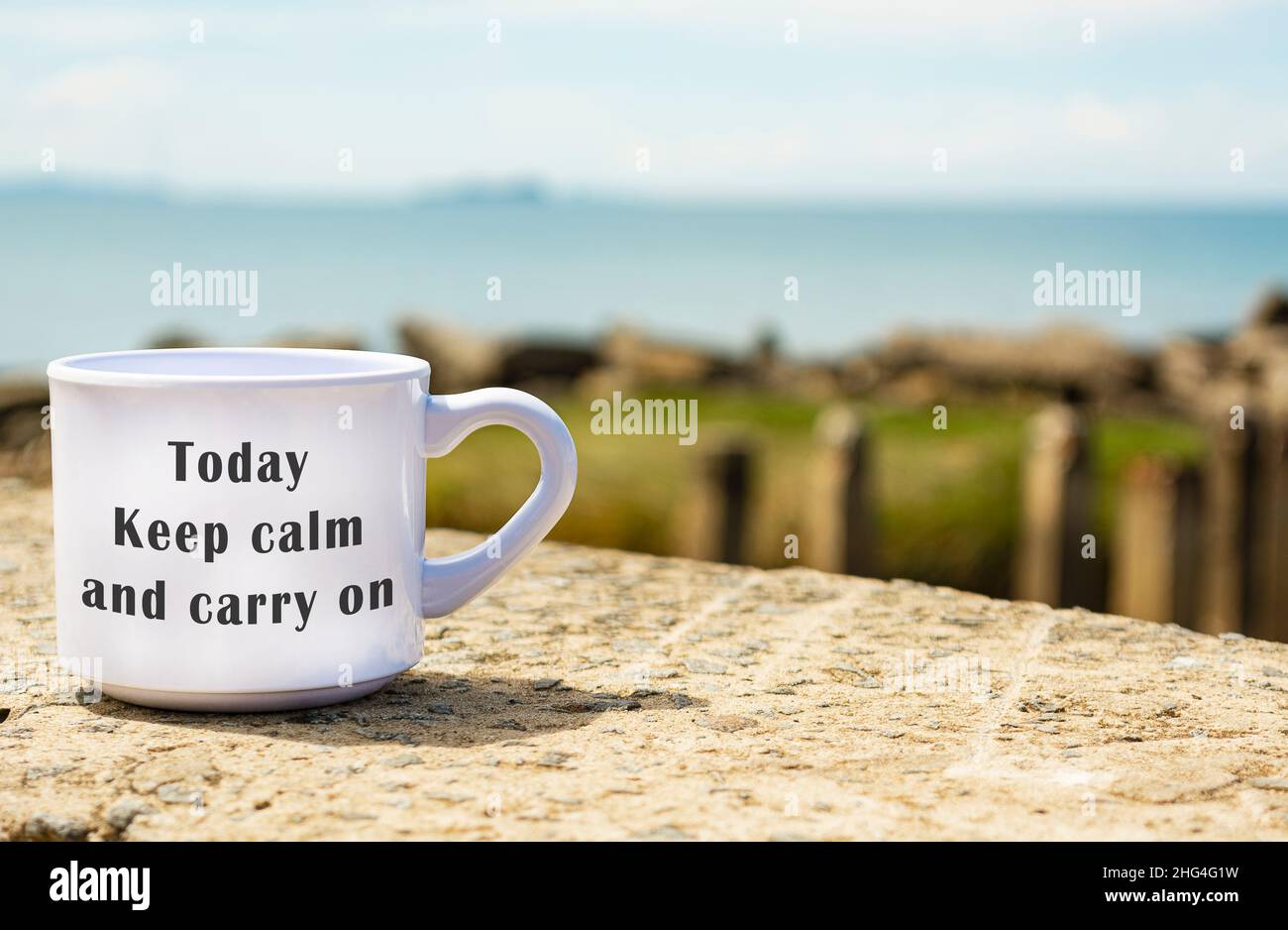 Citazione motivazionale e ispiratrice su una tazza di caffè con sfondo sfocato della spiaggia - oggi mantenere la calma e continuare Foto Stock