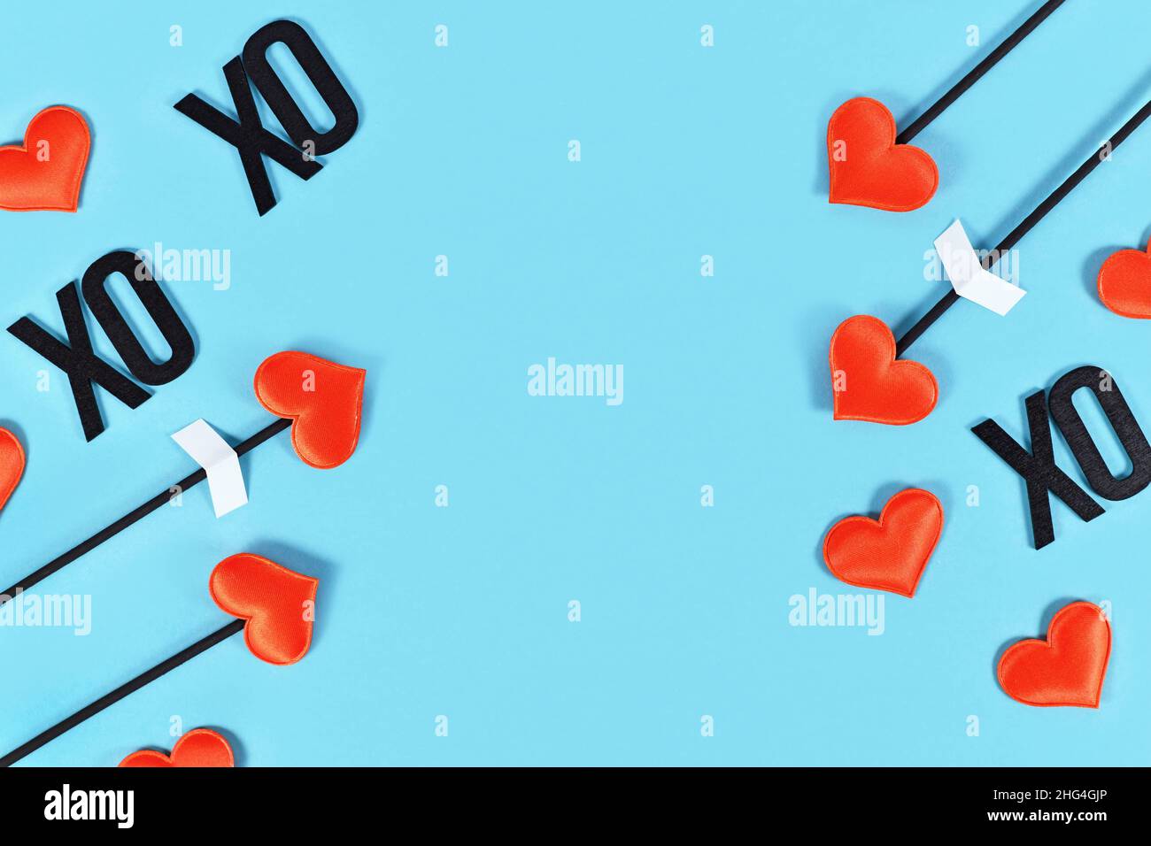 Appartamento di San Valentino posato con frecce d'amore Cupido e testo XOXO su sfondo blu con spazio copia Foto Stock