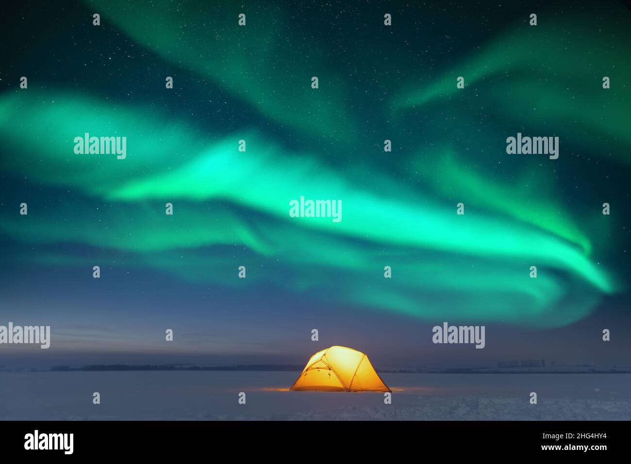 Tenda gialla illuminata dall'interno sullo sfondo di un incredibile cielo stellato con aurora boreale. Panorama notturno incredibile. Aurora boreale in campo invernale Foto Stock