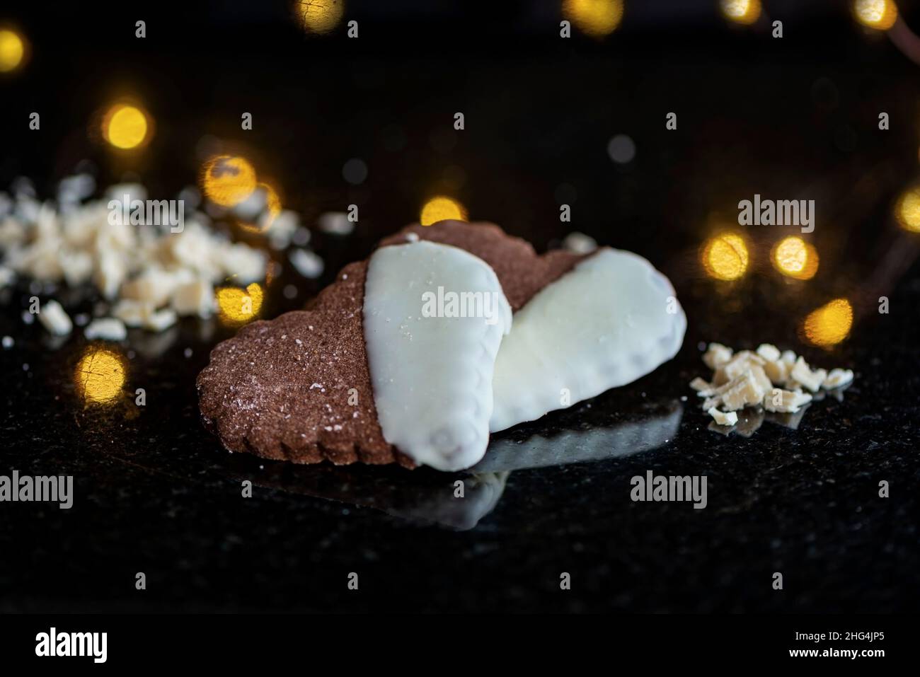 Deliziosi biscotti a forma di cuore su sfondo di marmo nero, primo piano, sfondo bokeh Foto Stock