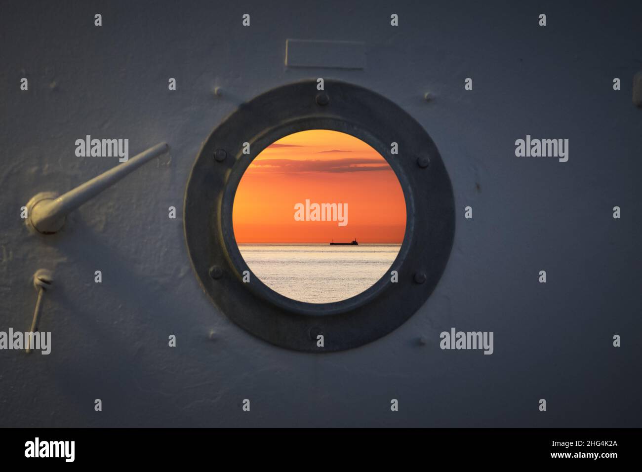 Nave da pesca solitaria trawler barca sull'acqua dell'oceano. Vista dalla finestra rotonda dalla cabina durante il tramonto. Mare calmo e limpido clima soleggiato. Bell'orizzonte di mare Foto Stock