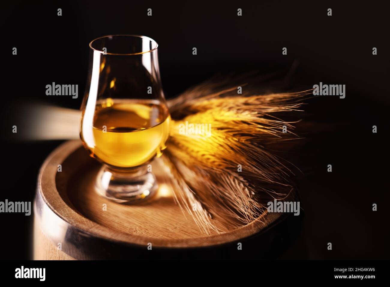 Un bicchiere di whisky sul vecchio barile di quercia con un mazzetto di segale. Tradizionale concetto di distilleria alcolica Foto Stock