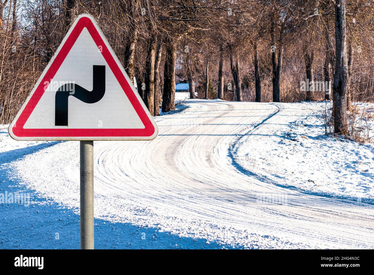 Cartello stradale su una strada coperta di neve tra gli alberi coperti di neve Foto Stock