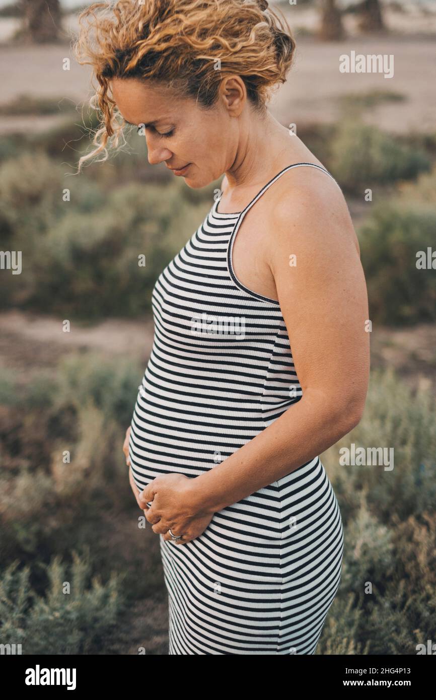 Donna matura 45 anni con pancia incinta in ritratto all'aperto. Stile di vita del neonato mummy del futuro. Donna adulta in attesa di bambini. Foto Stock