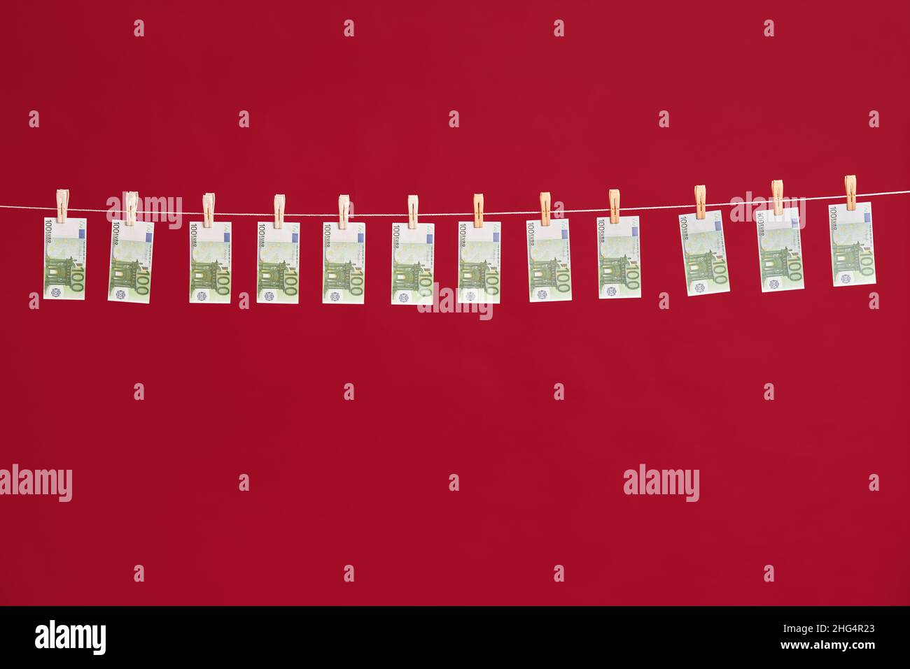 Riciclaggio di denaro, banconote in euro appese su corda su sfondo rosso studio. Finanza, corruzione, concetto di attività criminale Foto Stock