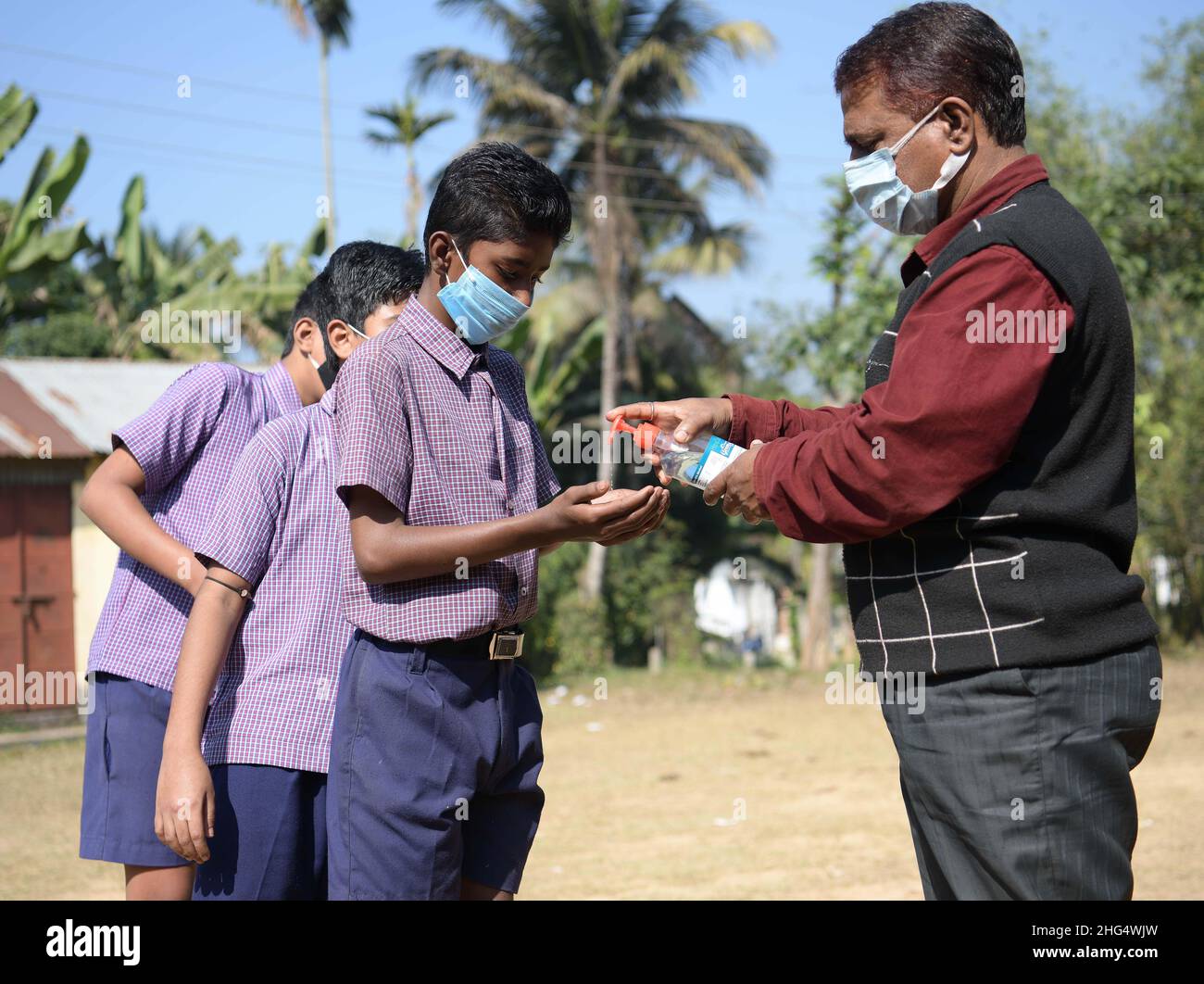 Gli studenti sanificano le mani prima di entrare in classe per gli esami in una scuola di Agartala. Tripura, India. Foto Stock