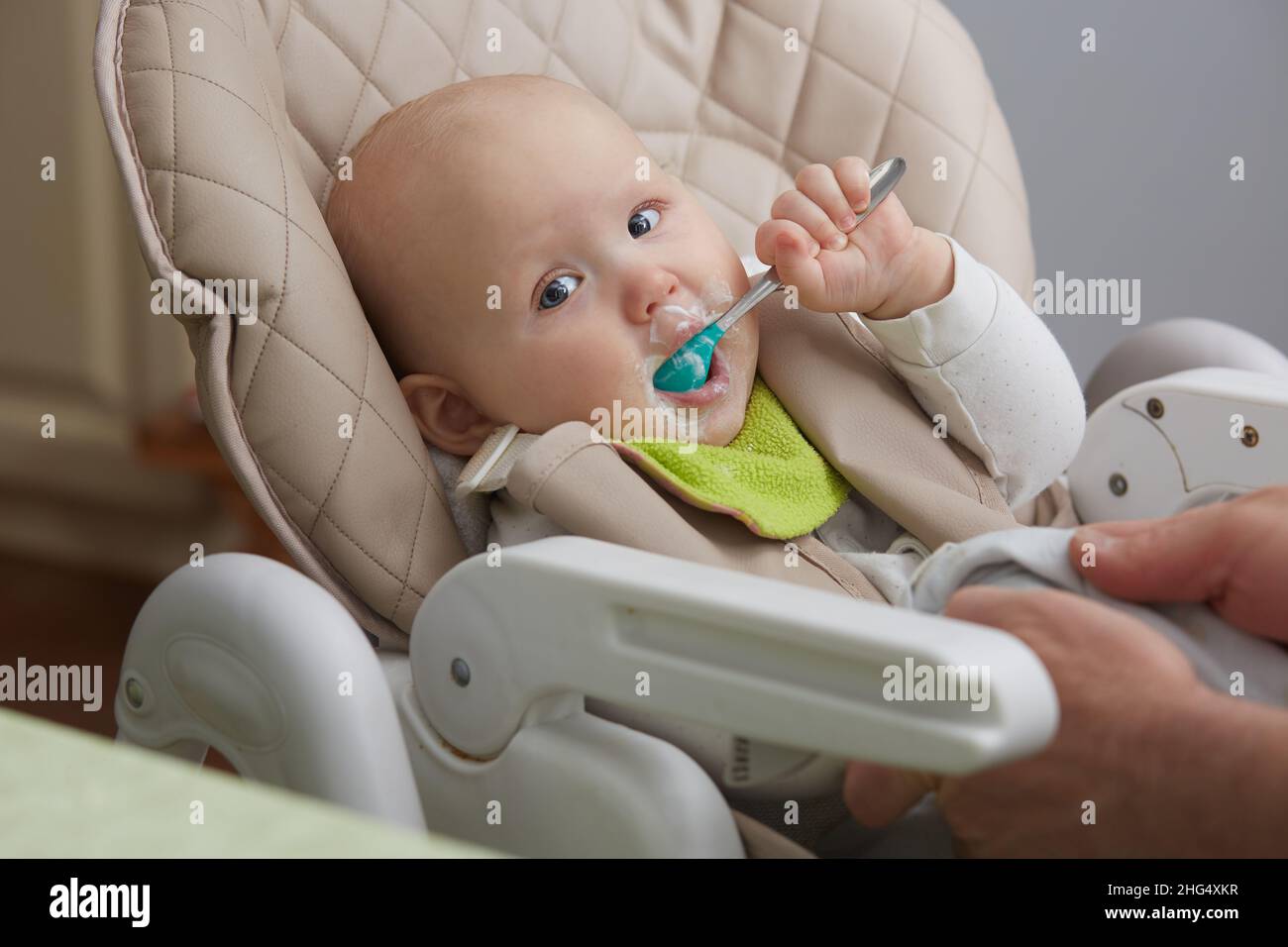 Il bambino mangia formaggio casolare seduto in una sedia del bambino Foto Stock