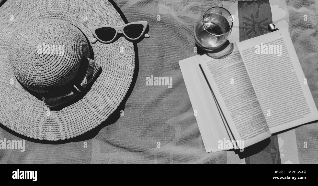 Concetto di vacanza estiva al mare con asciugamano, cappello e un libro, attività di svago in spiaggia in vacanza Foto Stock