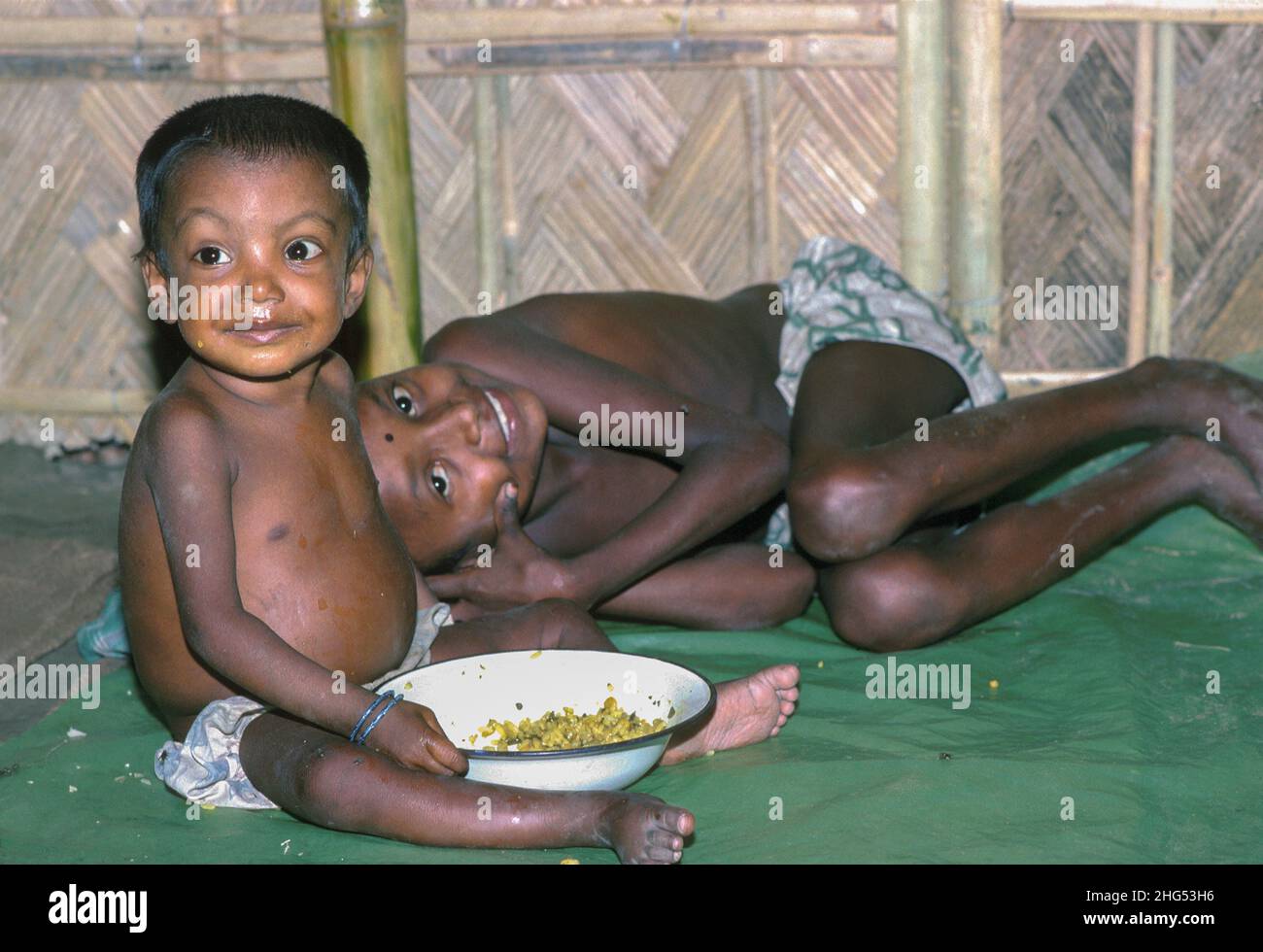 Due ragazzi dall'aspetto felice con una ciotola di cibo in un centro di alimentazione di emergenza allestito per gli sfollati durante gravi inondazioni. Jamalpur District, Bangladesh Foto Stock