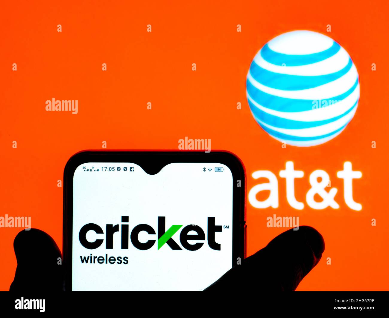 In questa figura, il logo Cricket viene visualizzato sullo schermo di uno smartphone con il logo AT&T sullo sfondo. Foto Stock