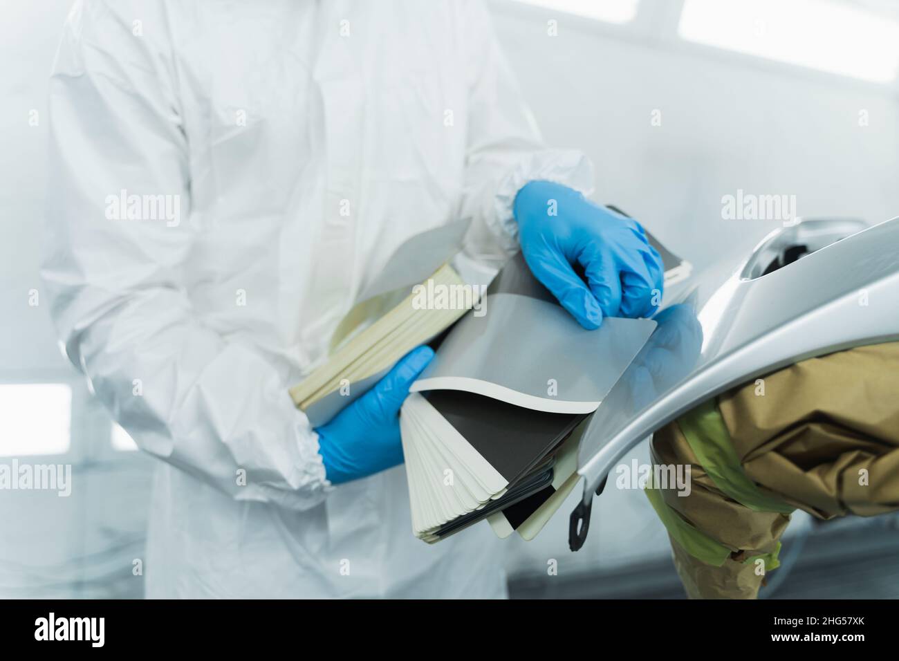 Il pittore automatico appoggia campioni di sfumature di colori di vernice contro gli elementi dell'automobile. Concetto di pittura dell'automobile Foto Stock