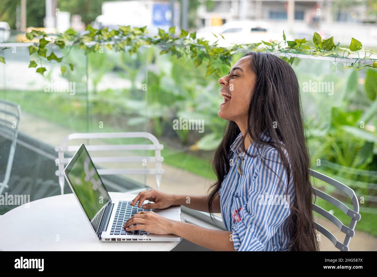 Giovane imprenditore femminile che utilizza il computer portatile mentre si siede sulla terrazza del caffè Foto Stock