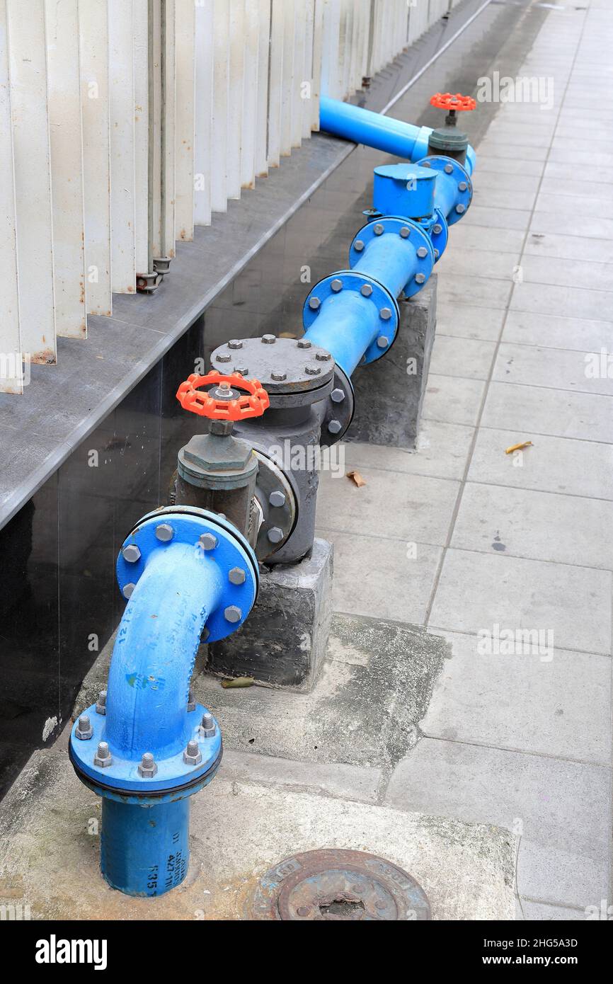 Valvola dell'acqua vicino al muro di cemento, tubi dell'acqua Uniti con il sistema di valvole di alimentazione dell'acqua sulla strada. Foto Stock