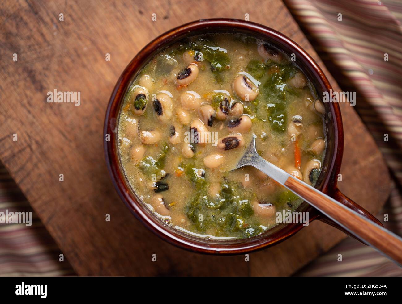 Vista dall'alto dei piselli con occhi neri e dei verdi di collardo in una ciotola marrone Foto Stock