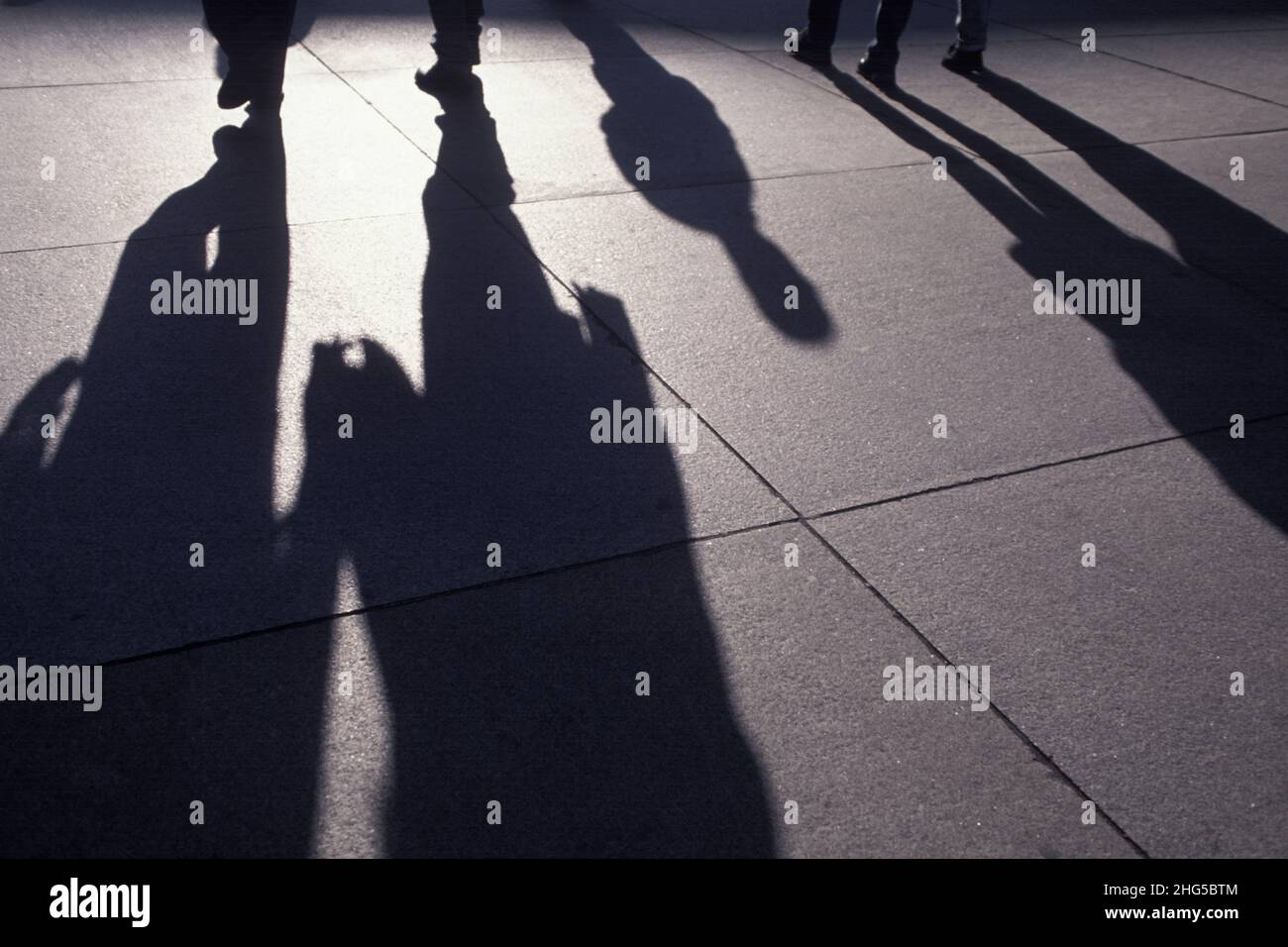 Ombre allungate sul marciapiede o sul marciapiede delle persone che camminano. Gruppo di pendolari irriconoscibili nell'ora di punta. New York, Stati Uniti Foto Stock