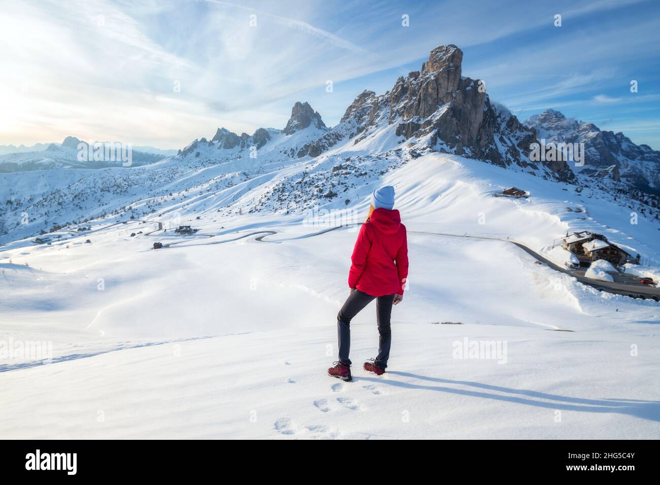 Giovane donna in giacca rossa in montagne innevate al tramonto in inverno Foto Stock