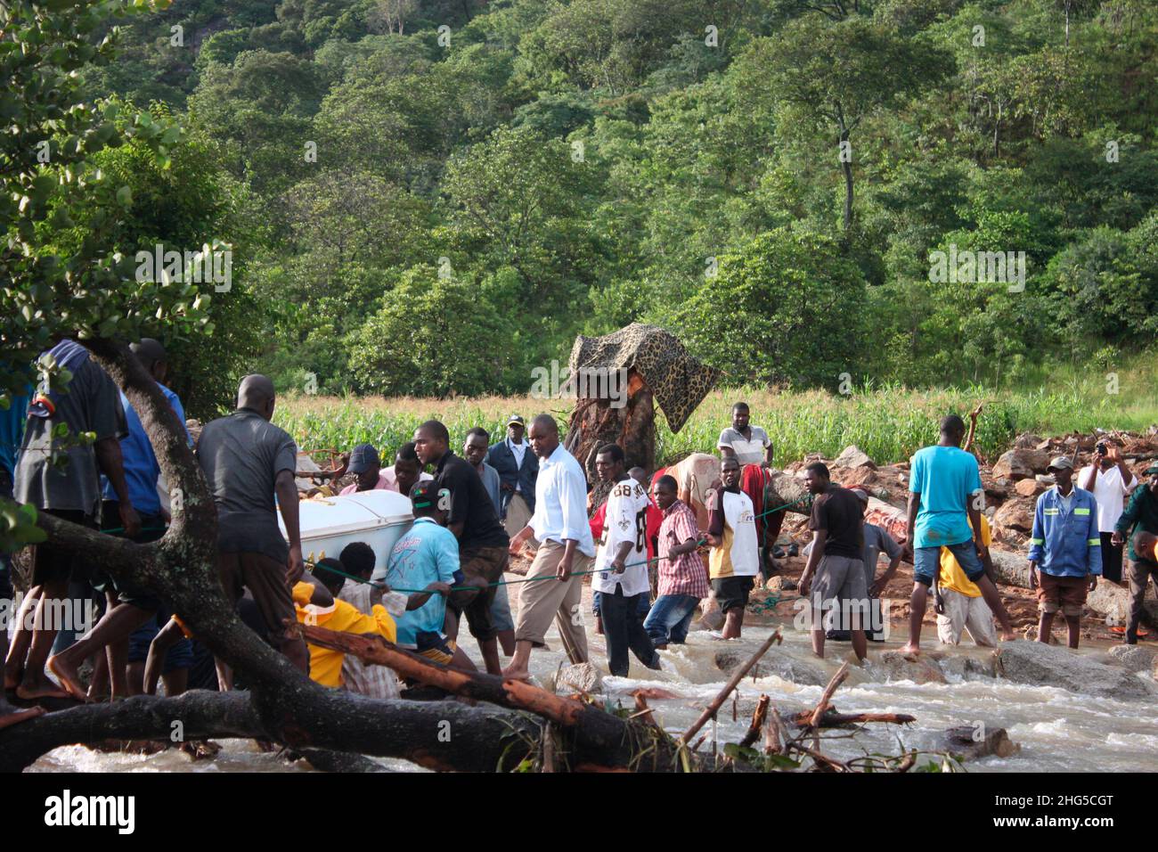 Amici e parenti si allineano attraverso il fiume Chipokoteke per garantire che la bara del compianto Freddy Chiusika attraversi in modo sicuro l'altro lato dove stava per essere sepolto. Chiusika fu ucciso in una frana che si appiattì e distrusse la sua casa. Zimbabwe. Foto Stock