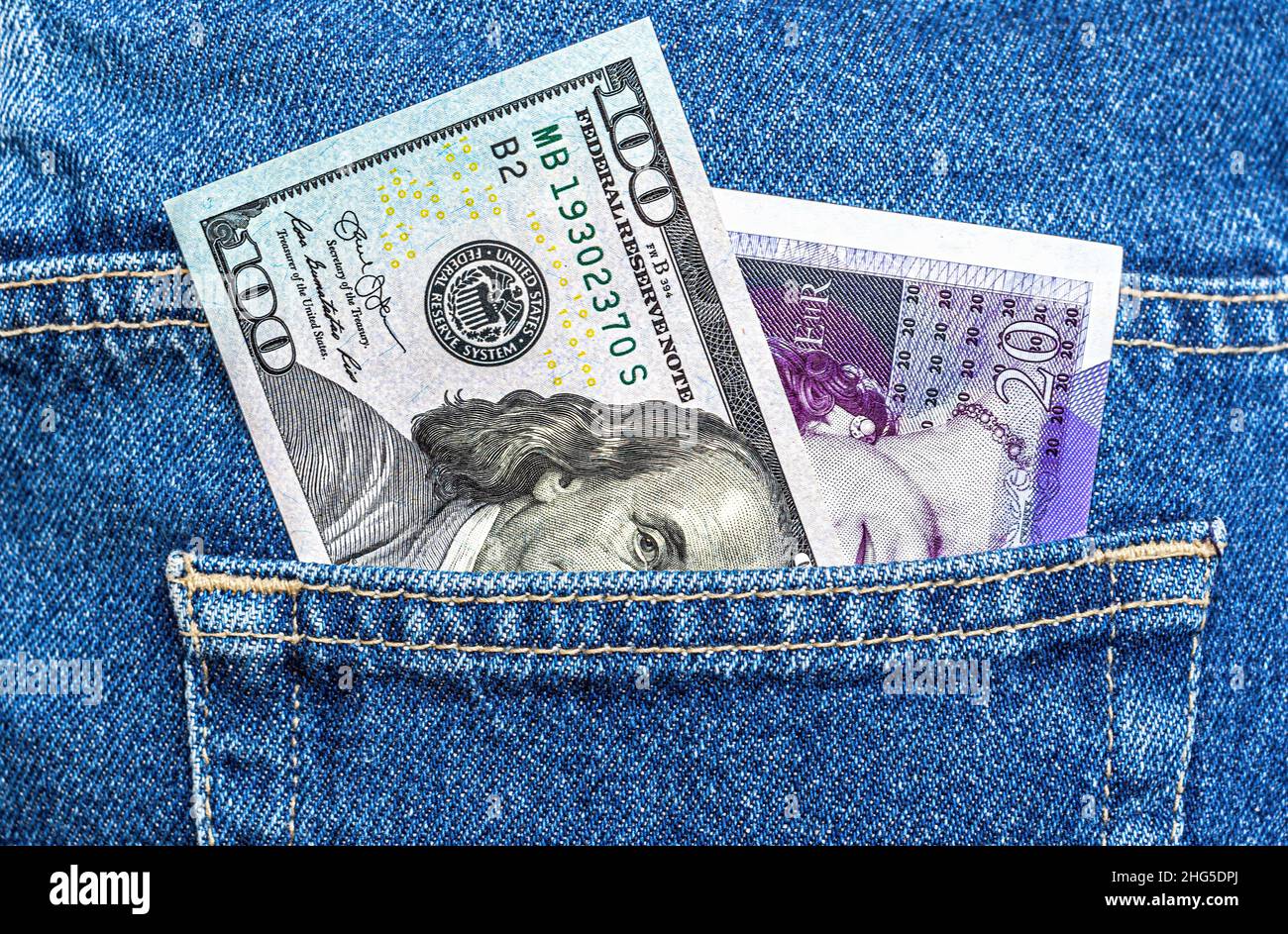 Banconote in dollari americani e sterline britanniche sporgono dalla tasca dei jeans da vicino Foto Stock
