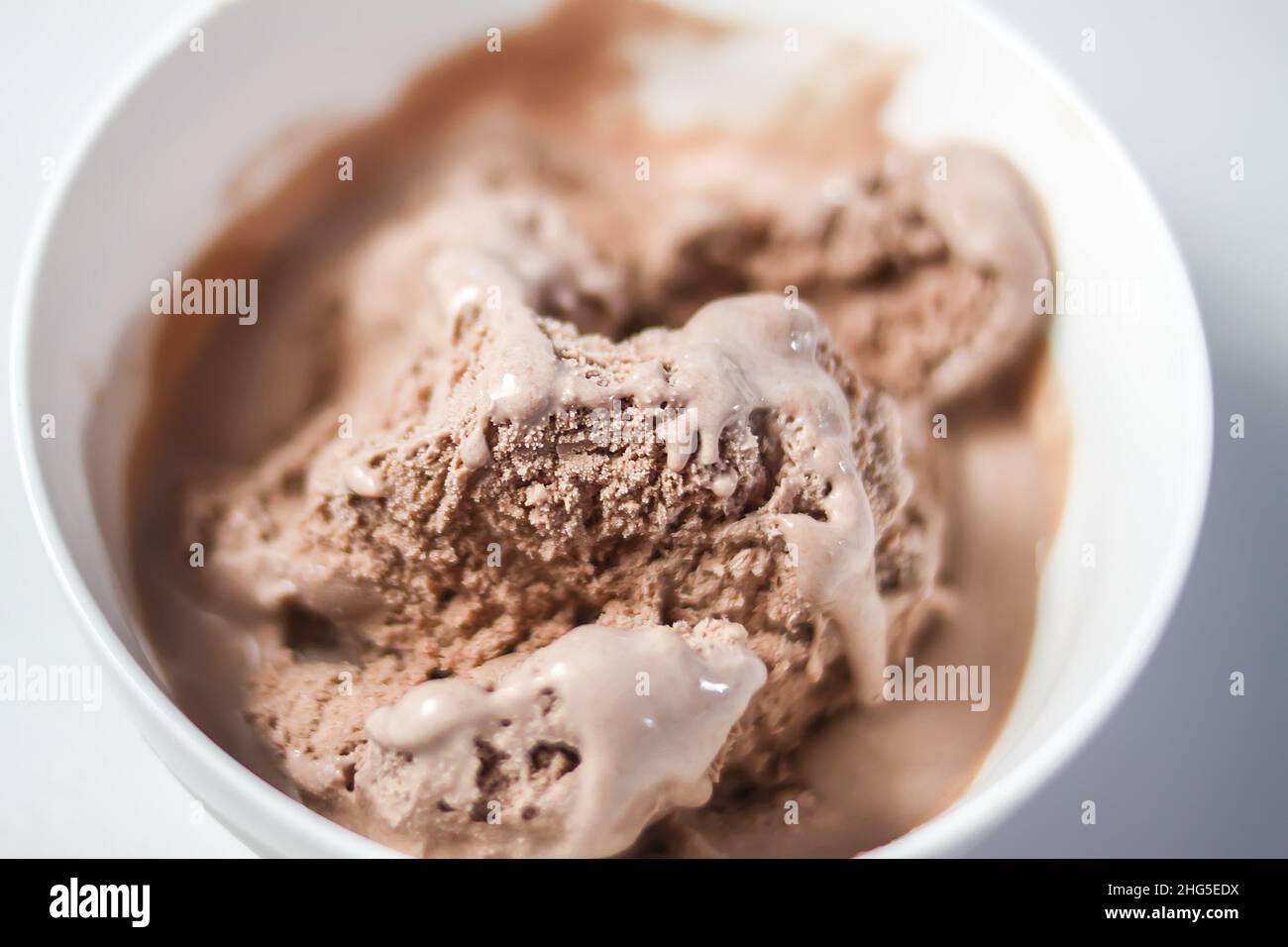 Fondendo il gelato al cioccolato in una tazza di ceramica bianca. Foto Stock