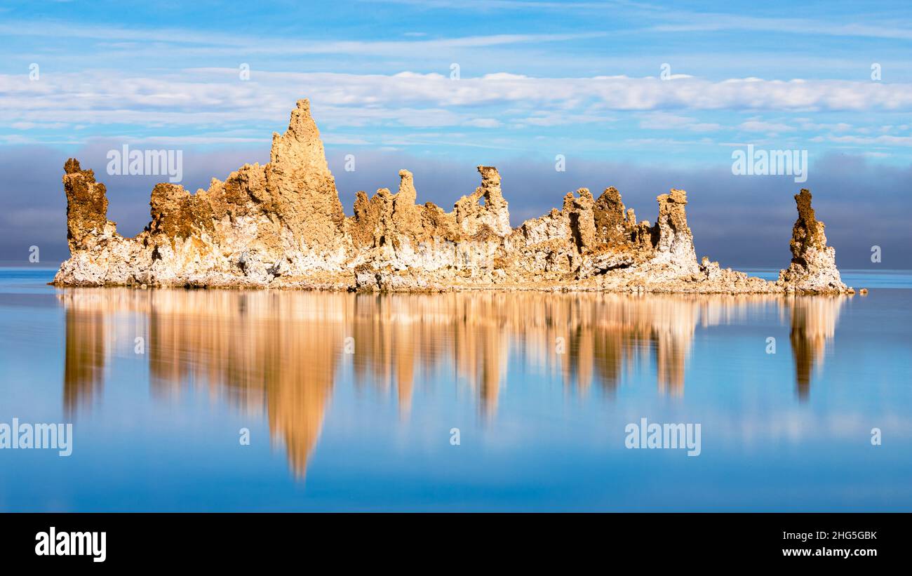 Grande formazione di tufo nel lago di Mono nella contea di Mono, California, USA. L'immagine presenta riflessi e nuvole modiche/basse sullo sfondo. Foto Stock