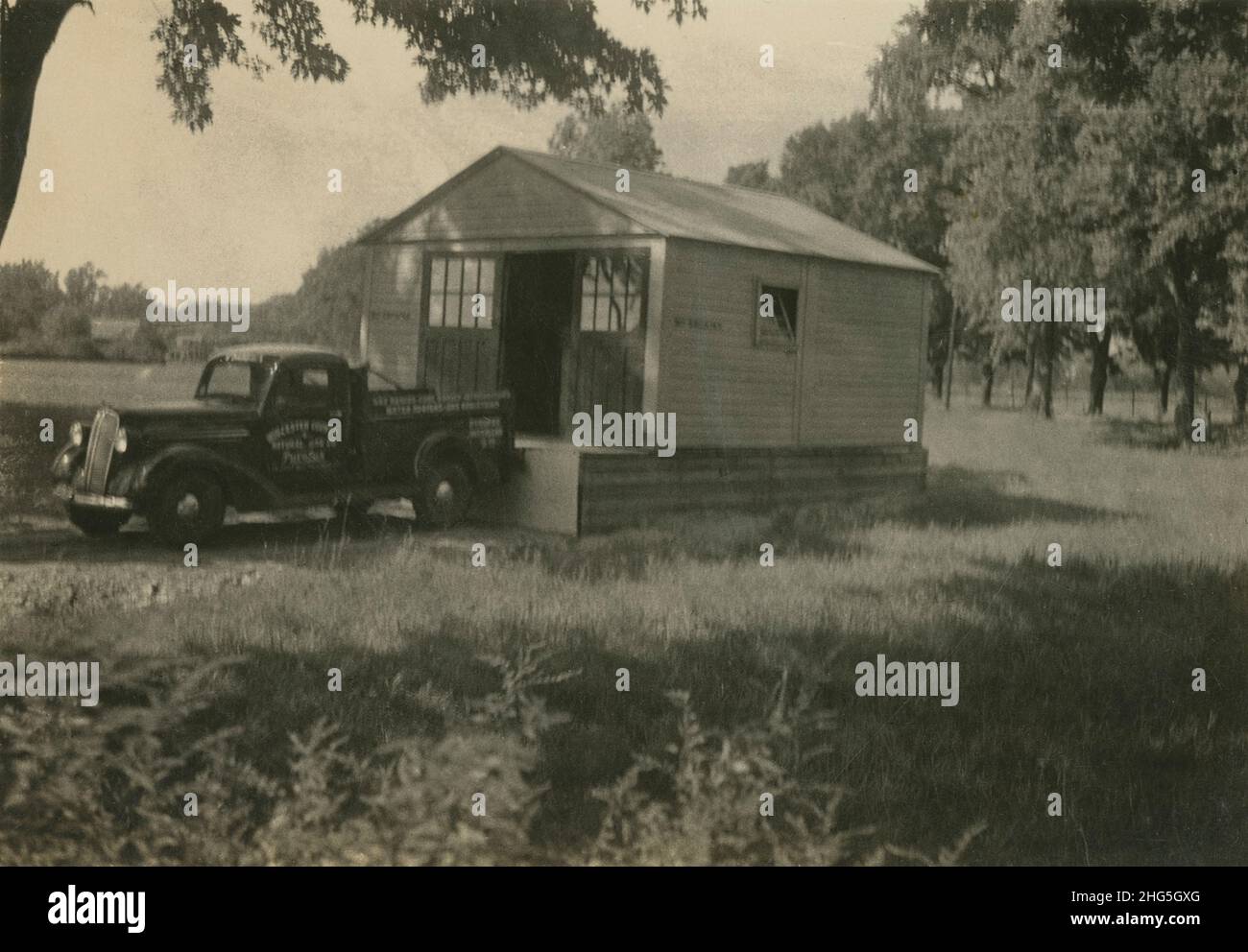 Fotografia antica del 1940 circa, camion di pick up sostenuto fino alla costruzione di officina. Il veicolo è un pick-up da mezza tonnellata Chevrolet serie GC 1937. Posizione esatta sconosciuta, forse Massachusetts, Stati Uniti. FONTE: FOTOGRAFIA ORIGINALE Foto Stock