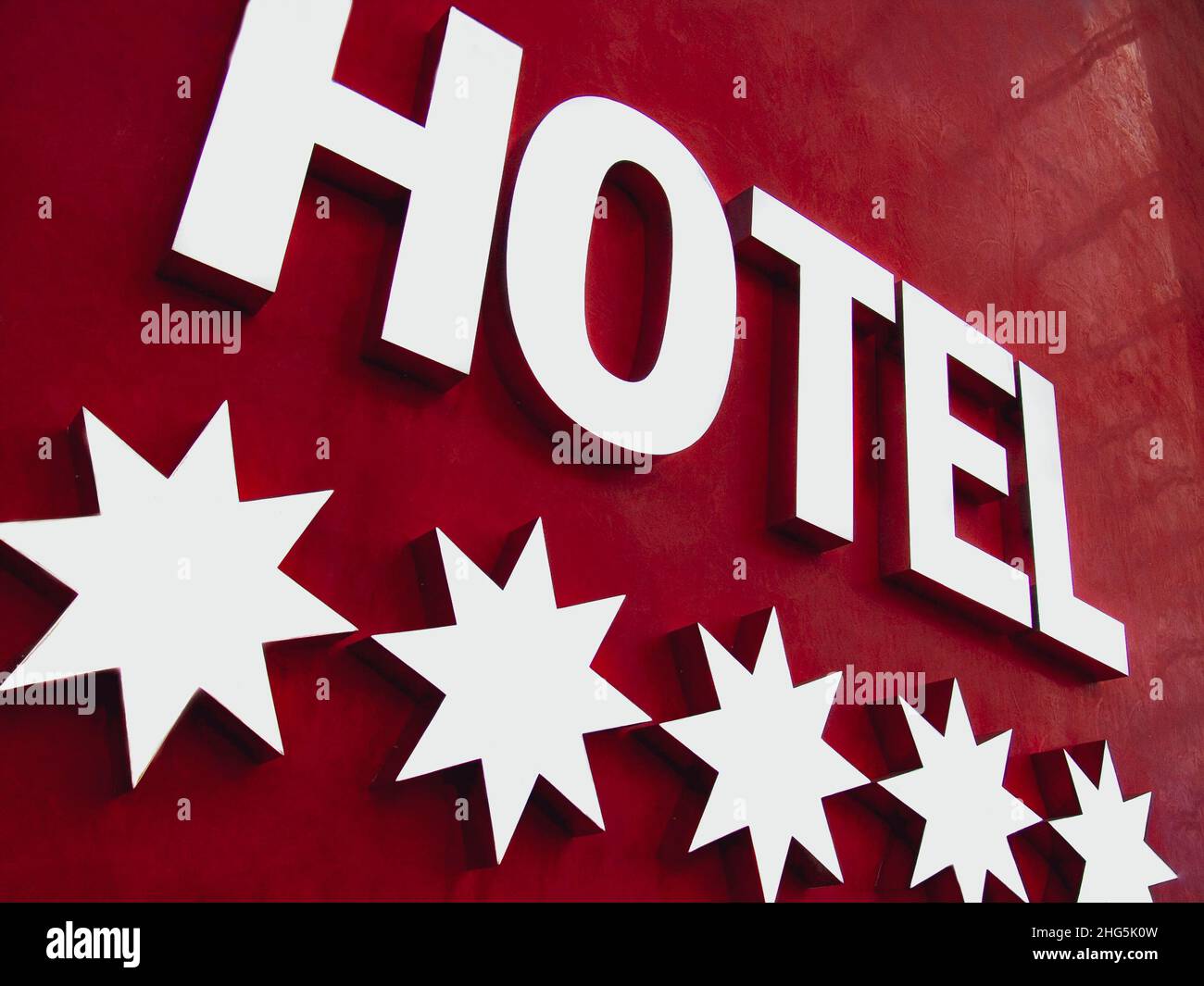 HOTEL a 5 STELLE ILLUMINATO SEGNO metallo riflettente cinque stelle segno hotel su sfondo rosso parete Foto Stock
