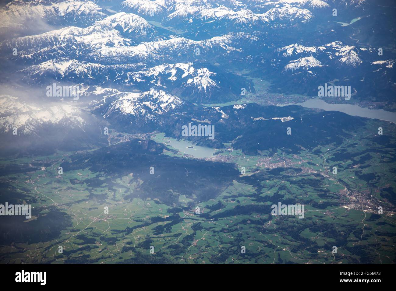 Nuvole bianche prese da un aereo in movimento. Verde natura e montagne con neve sotto. Volare in aria. Corsa in aereo. Foto di alta qualità Foto Stock