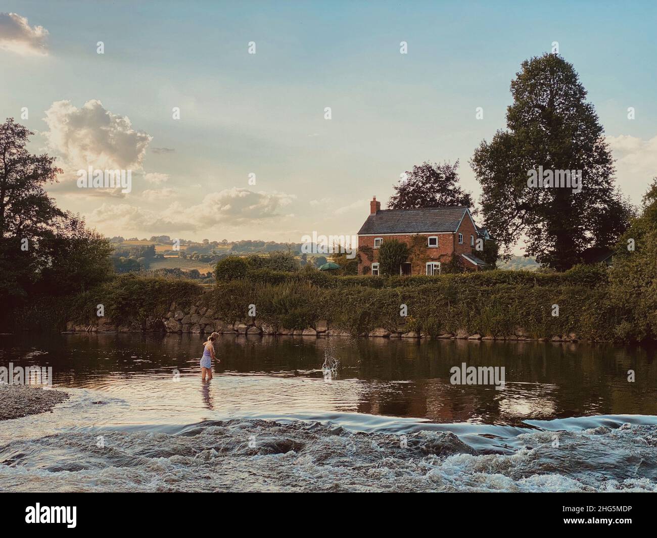 Ragazza adolescente skimming pietre sul fiume Wye al crepuscolo Foto Stock