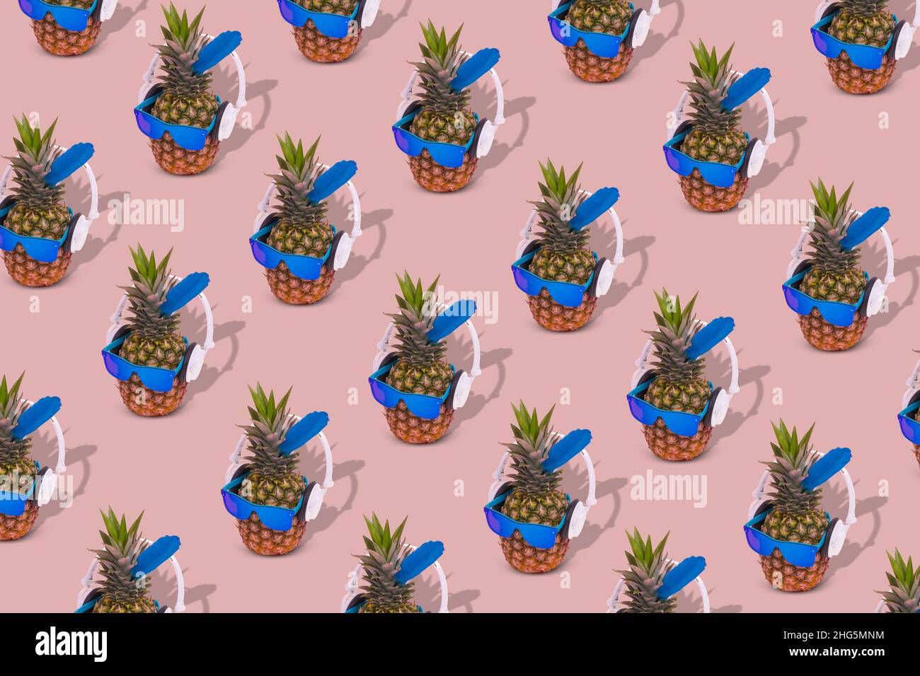 Motivo estivo creativo e alla moda con occhiali da sole e cuffie ananas su sfondo rosa pastello. Scena creativa di divertimento, festa, moda, tren Foto Stock