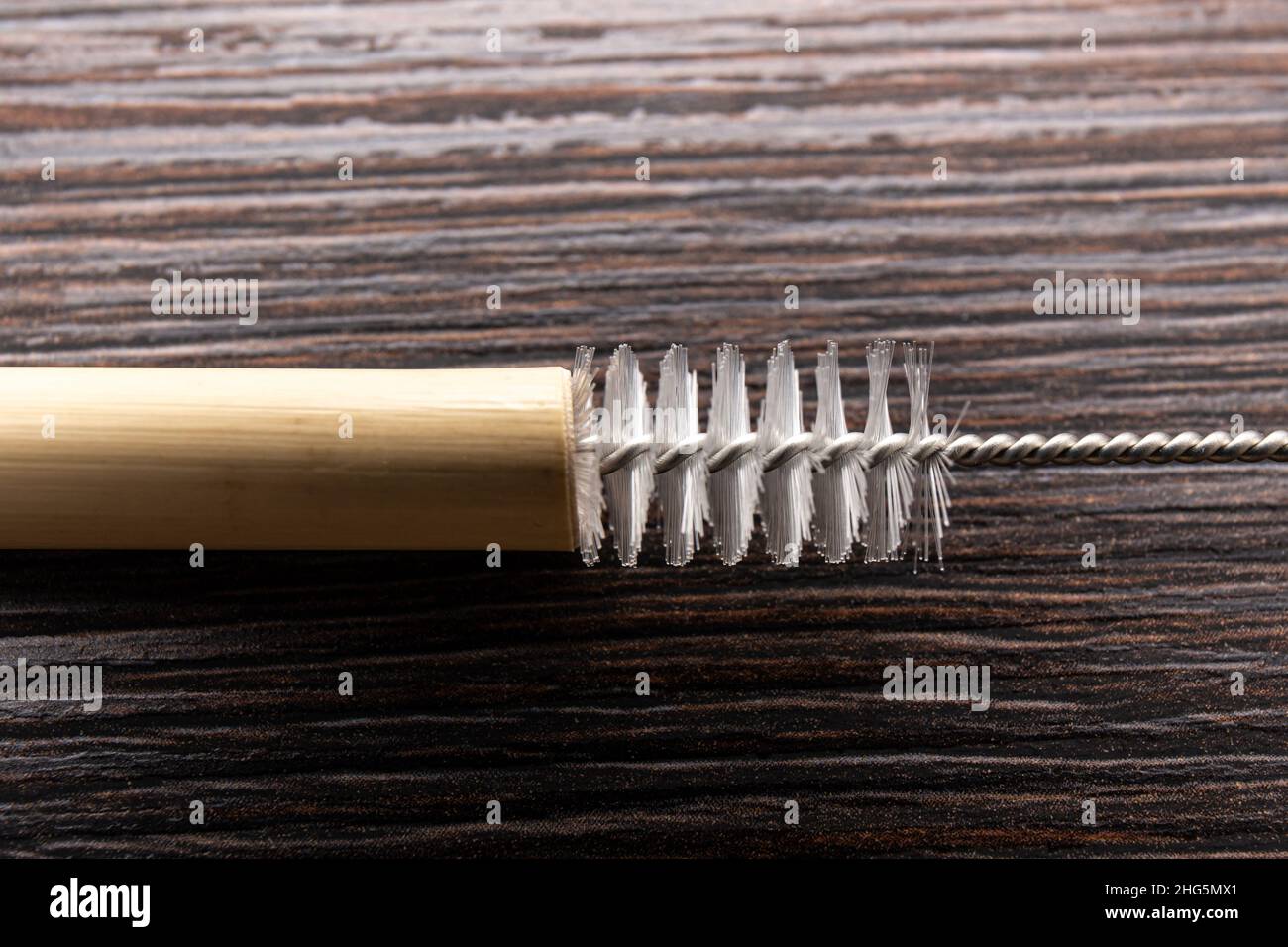 Vista ravvicinata dell'uso della spazzola per la pulizia della paglia potabile per pulire la paglia potabile di bambù riutilizzabile, in casa. Foto Stock