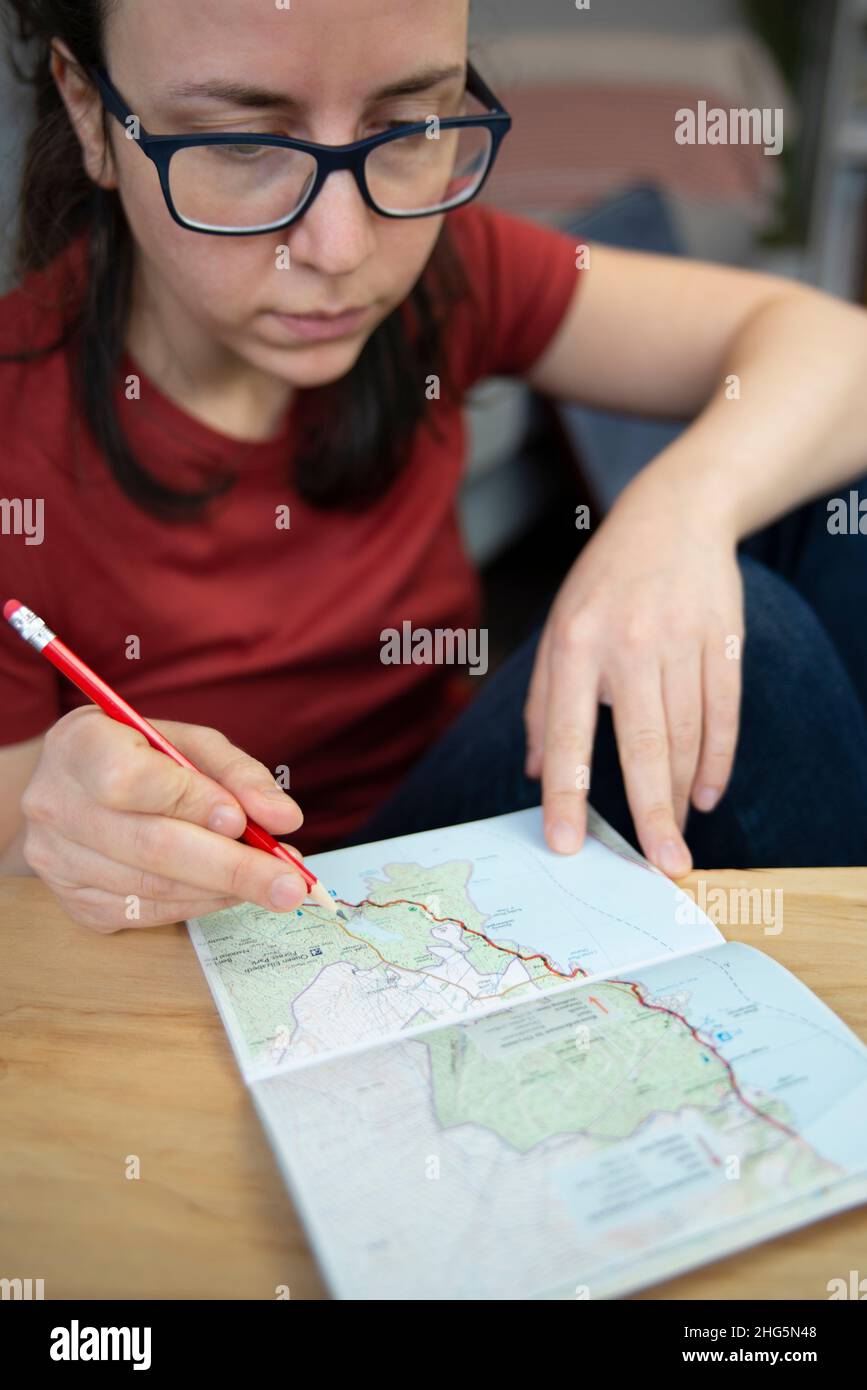 Persona che pianifica un viaggio con una mappa e una guida cartacea Foto Stock