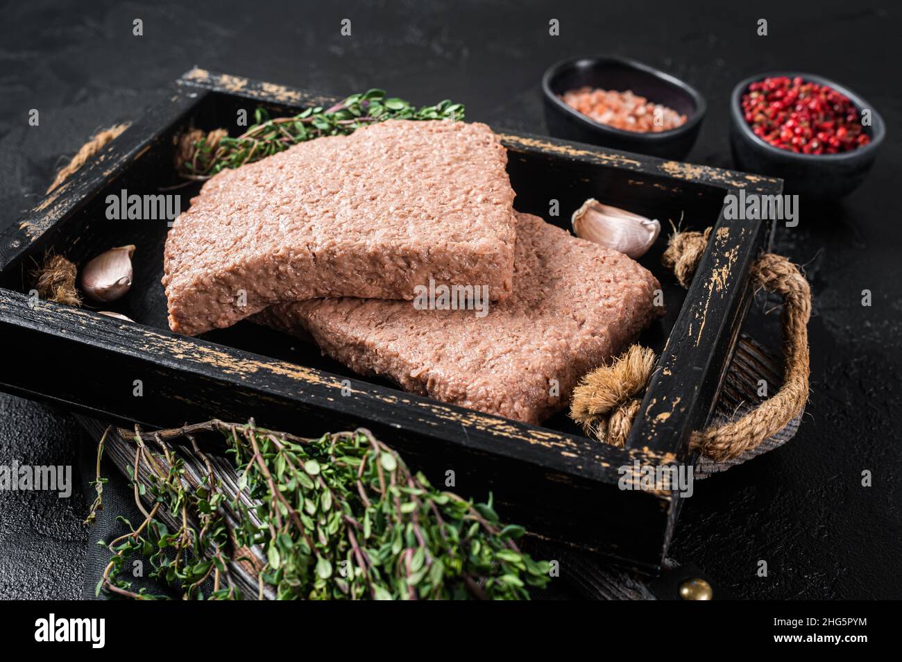Carne di trita vegana a base di piante crude con erbe aromatiche. Sfondo nero. Vista dall'alto Foto Stock