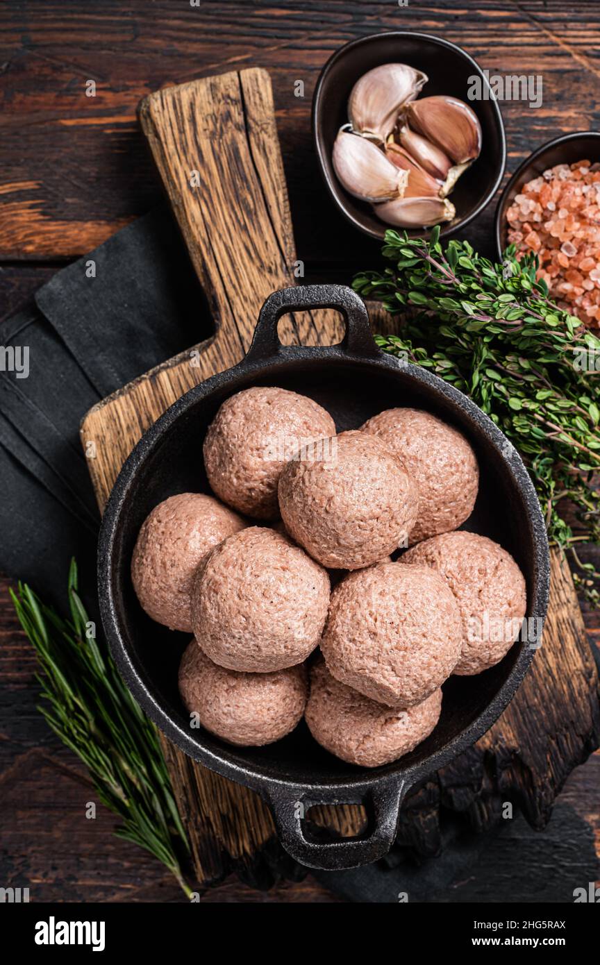 Polpette vegetariane senza polpette di carne cruda a base di piante con timo e rosmarino. Sfondo in legno. Vista dall'alto Foto Stock