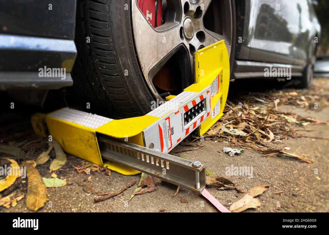 Un'auto con un morsetto per ruota, un bagagliaio per ruota o un bagagliaio per parcheggio, un'auto con un'auto avviata per violazione del parcheggio Foto Stock