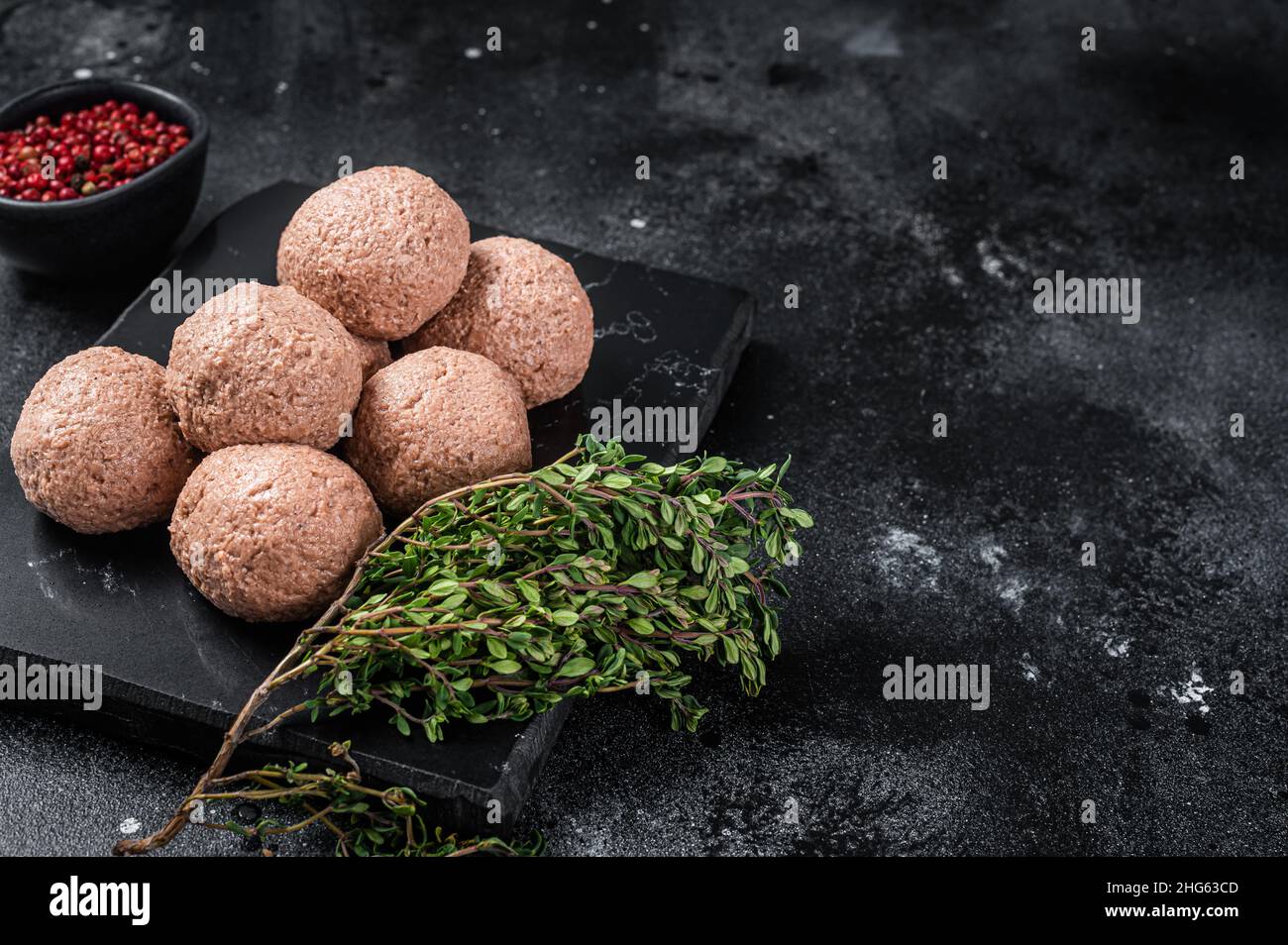 Polpette di vegano crude di carne vegetale con timo. Sfondo nero. Vista dall'alto. Spazio di copia Foto Stock