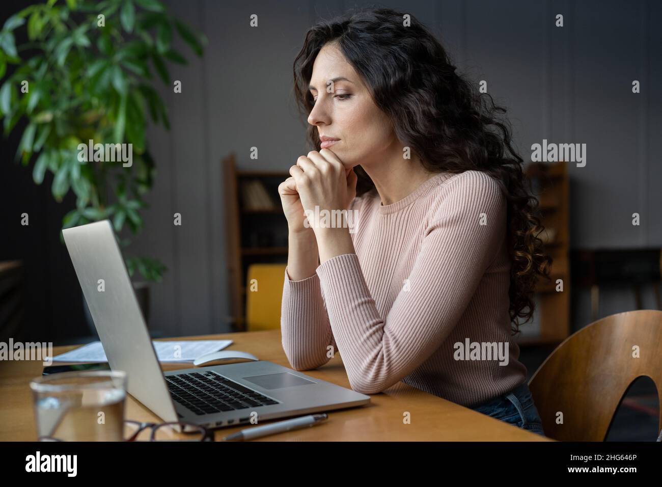 Donna d'affari focalizzata che lavora su laptop, commercialista che legge documento elettronico finanziario Foto Stock