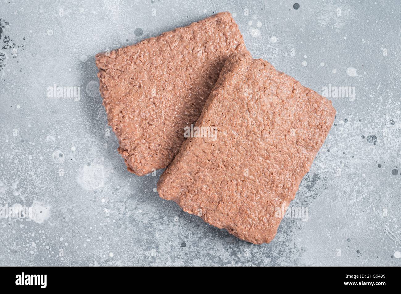 La carne a base di piante crude, gli alimenti riducono l'impronta di carbonio. Sfondo grigio. Vista dall'alto Foto Stock