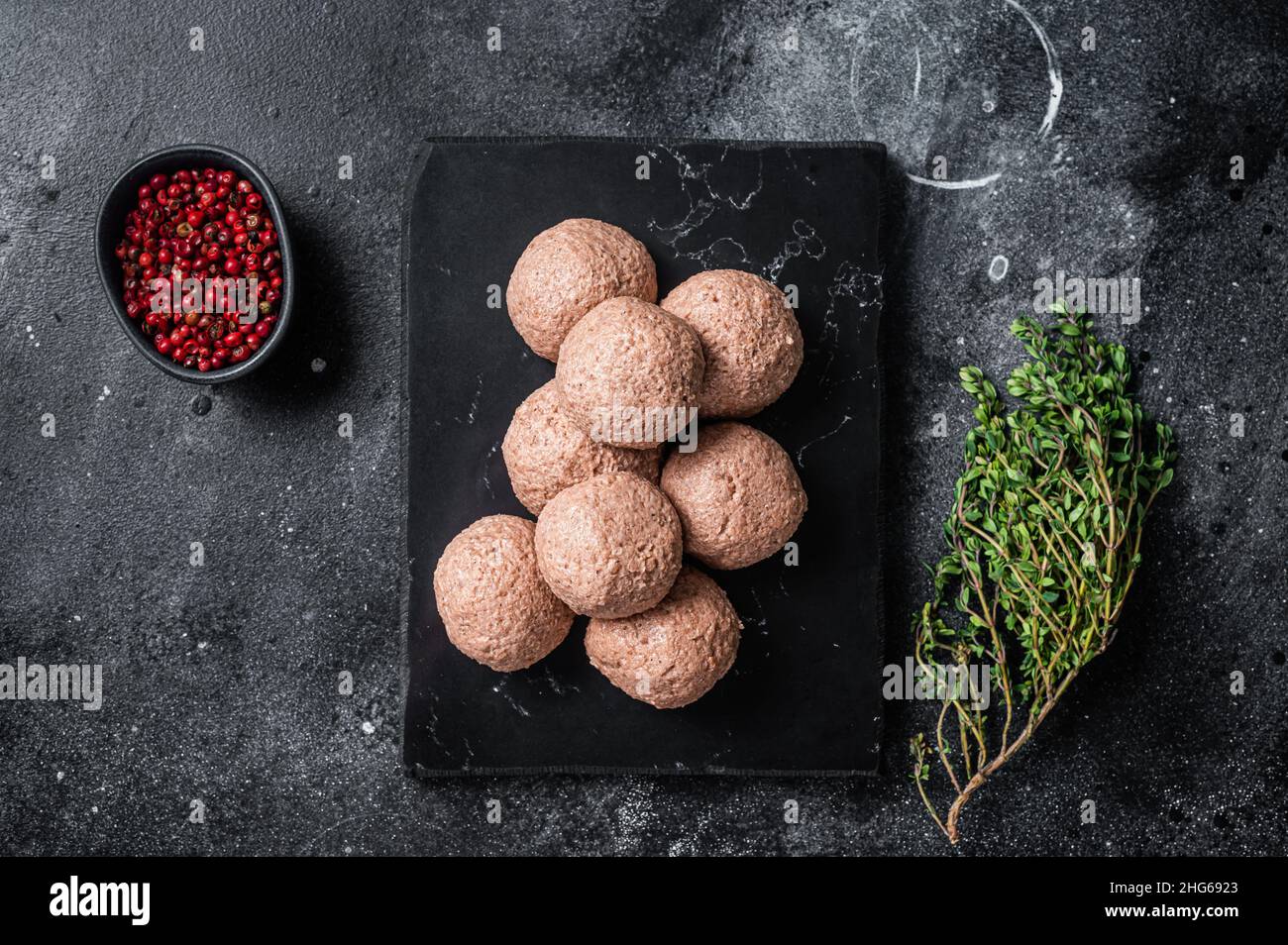 Polpette di vegano crude di carne vegetale con timo. Sfondo nero. Vista dall'alto Foto Stock