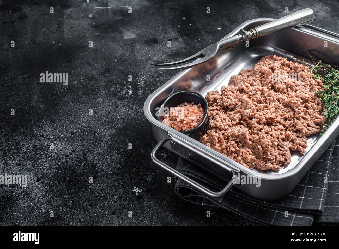 Carne vegetariana macinata, carne cruda a base di piante con erbe in cucina vassoio sfondo nero. Vista dall'alto. Spazio di copia Foto Stock