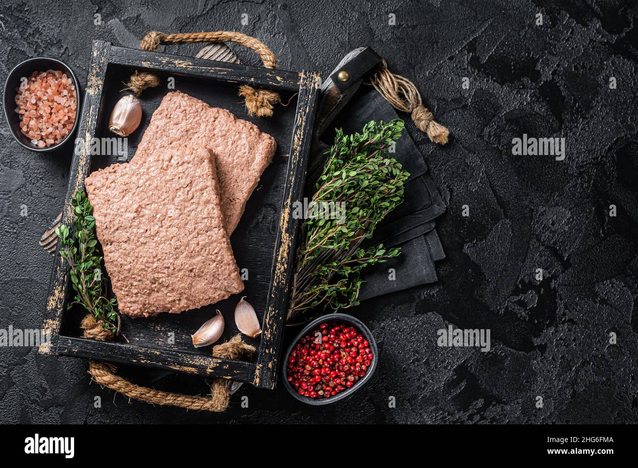 Carne di trita vegana a base di piante crude con erbe aromatiche. Sfondo nero. Vista dall'alto. Spazio di copia Foto Stock