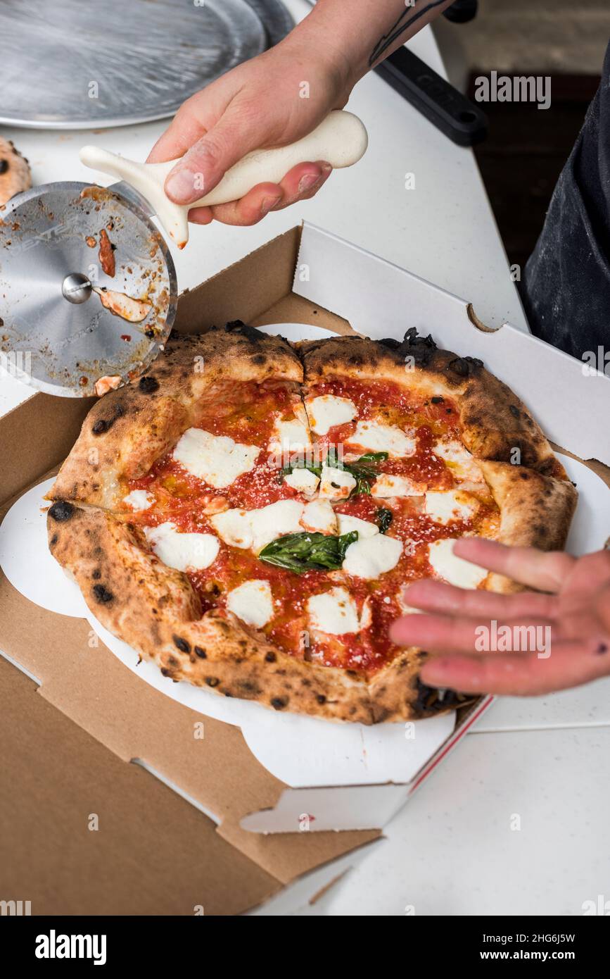Pizzaiolo affettare la torta Margherita appena sfornata Foto Stock