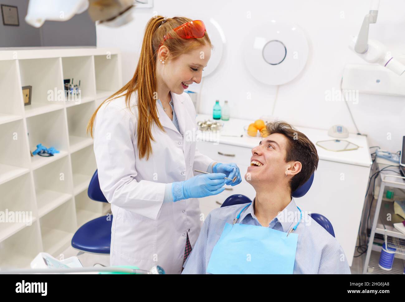 Da sopra l'uomo e la donna sorridendo e guardandosi durante l'appuntamento in studio dentista contemporaneo Foto Stock