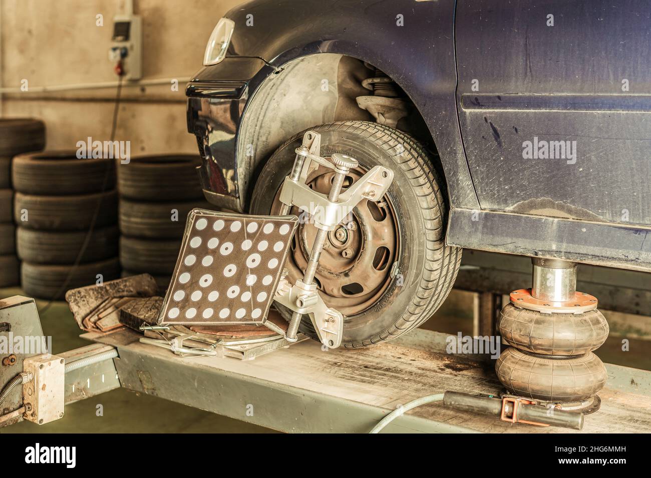 Attrezzo montato sulla ruota di una vettura per l'allineamento dello sterzo in officina Foto Stock